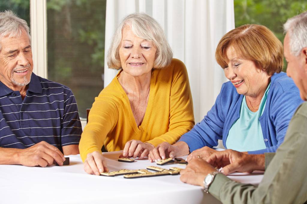 Group of senior people in assisted living community playing domino game
