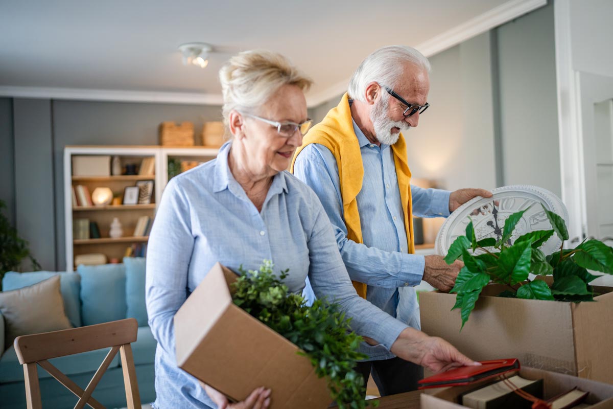 Senior couple packing up boxes of belongings, getting ready to relocate to assisted living